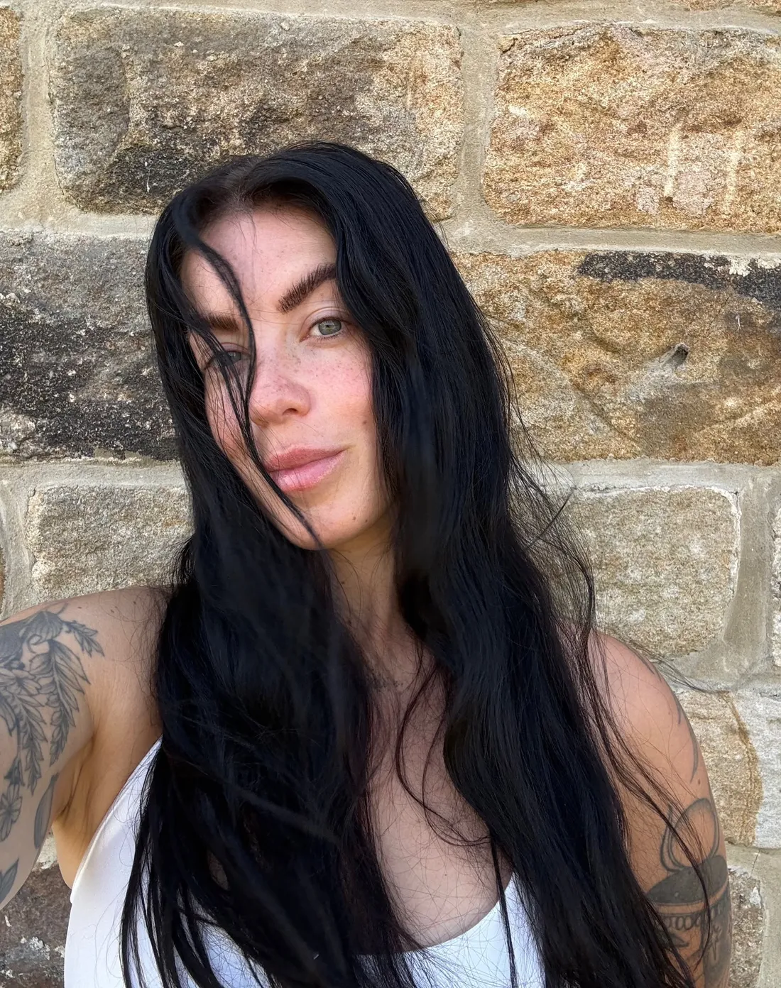 Erin, founder of Feral Kin, standing against a stone wall